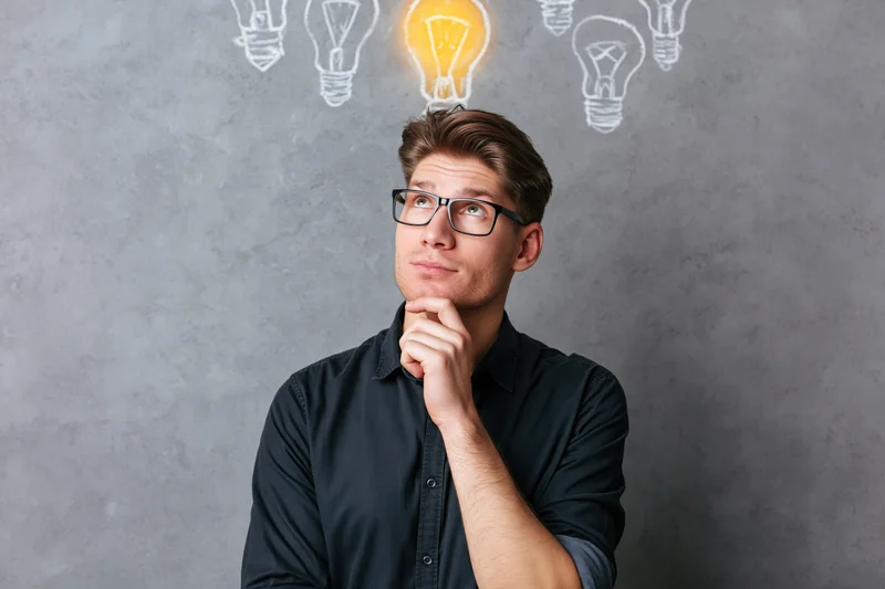 Man thinking with glowing lightbulb above his head against grey concrete wall