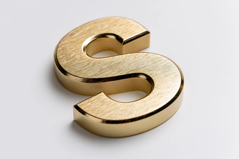 Golden three-dimensional letter s on white background with soft shadow