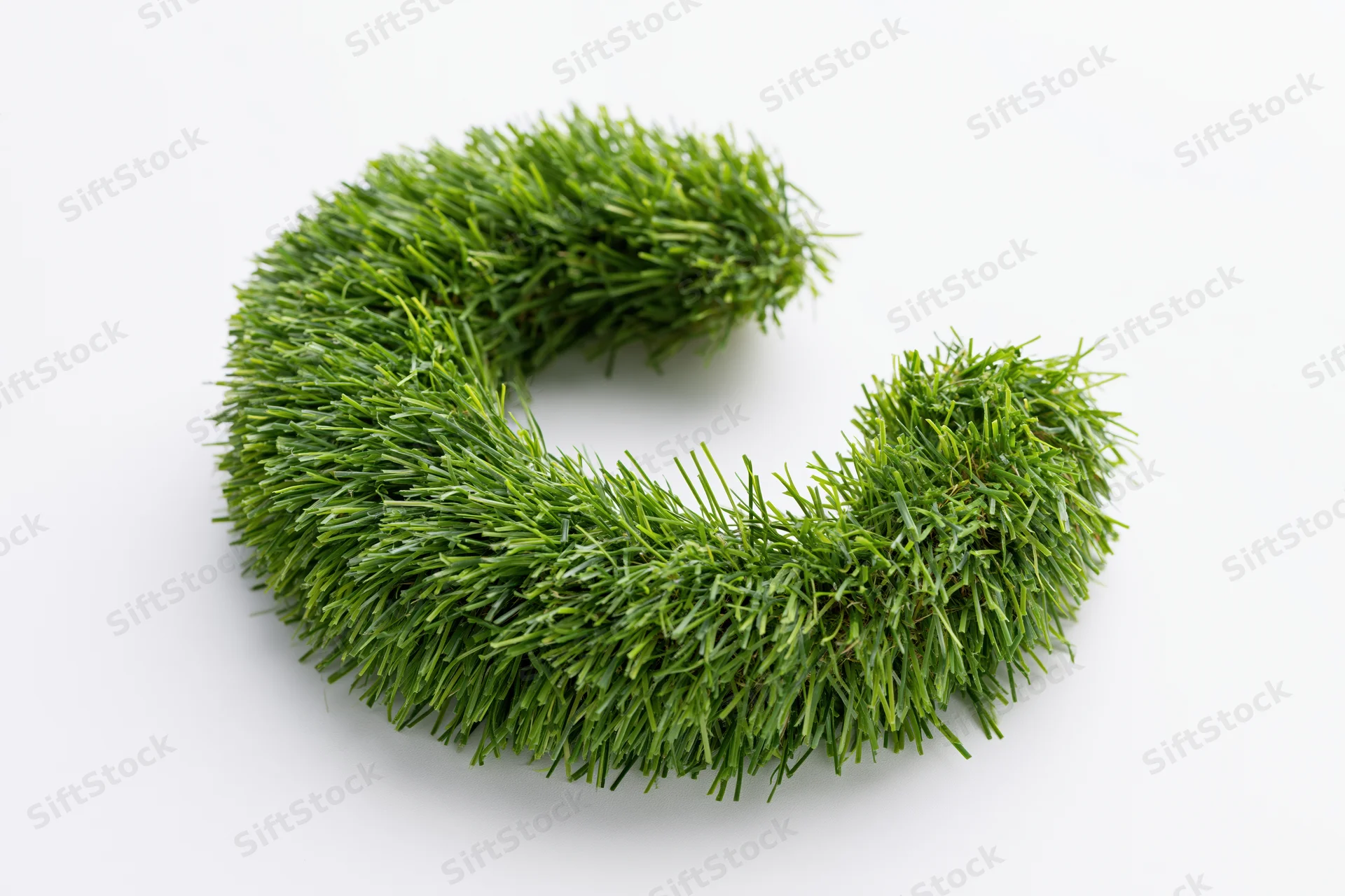 A grassy letter c shape formed from dense green blades on a white surface