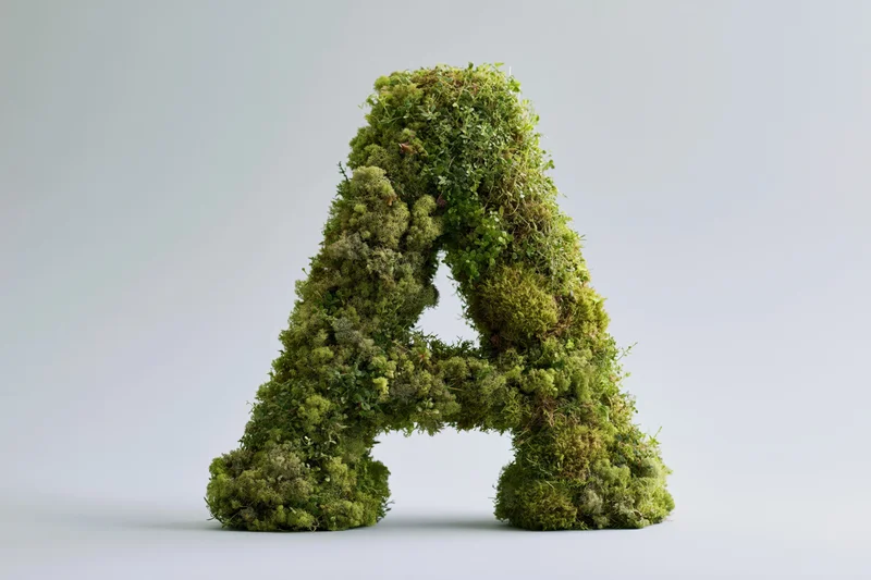Moss-covered capital letter A sculpture on white background