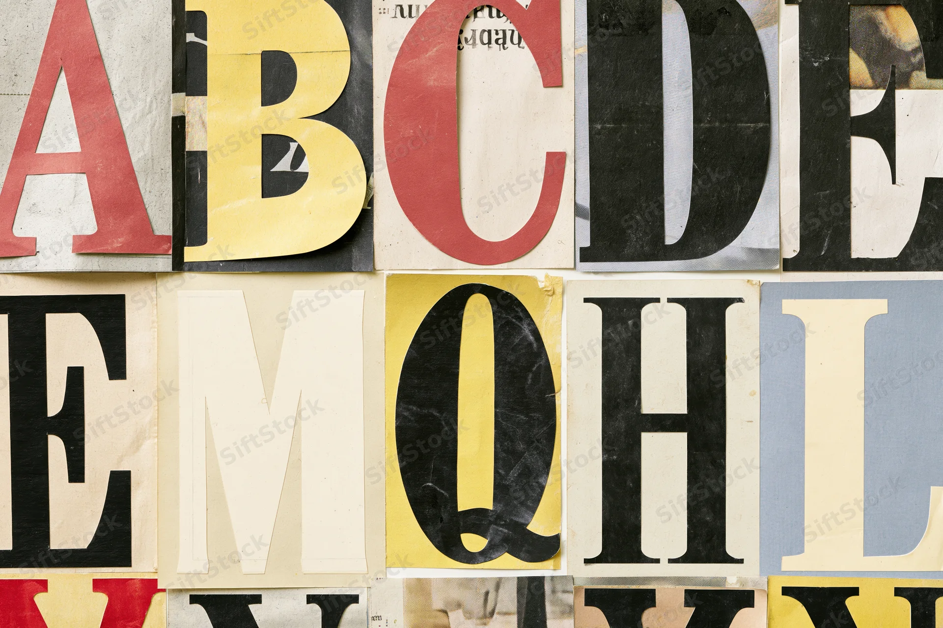 Cut-out alphabet letters arranged in a grid on a textured surface