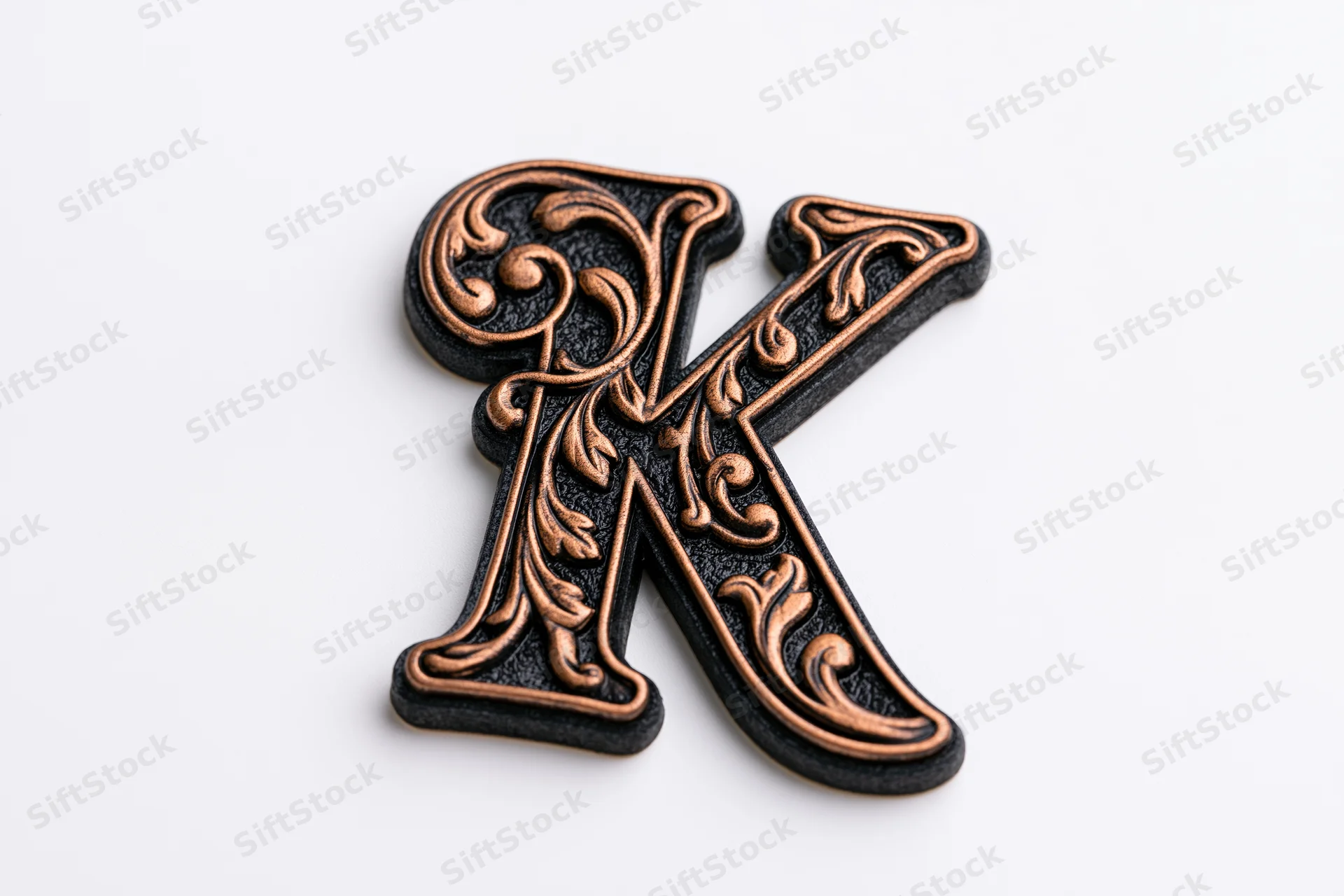 Ornate three-dimensional letter k with floral patterns on white background