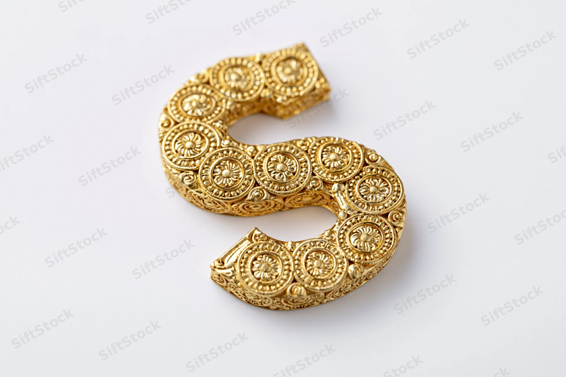 Ornate gold letter s with floral patterns on white background