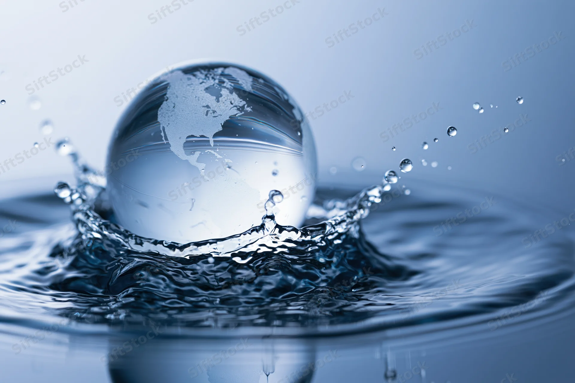 Glass globe resembling earth emerging from a water splash with ripples and droplets