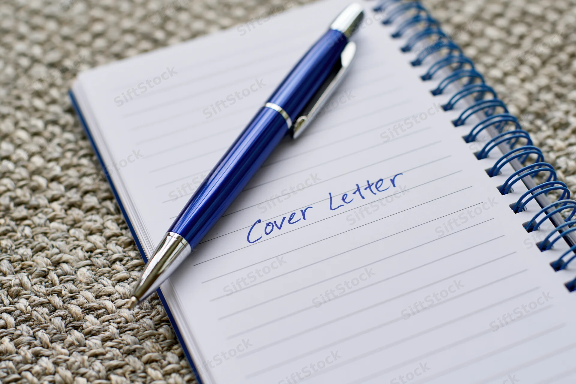 Blue pen resting on open notebook with handwritten cover letter on lined paper