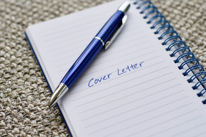 Blue pen resting on open notebook with handwritten cover letter on lined paper