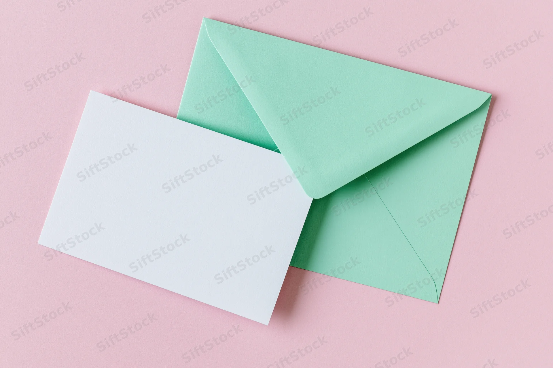 Mint green envelope with blank white card on pink background