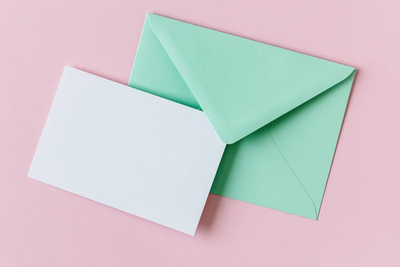 Mint green envelope with blank white card on pink background