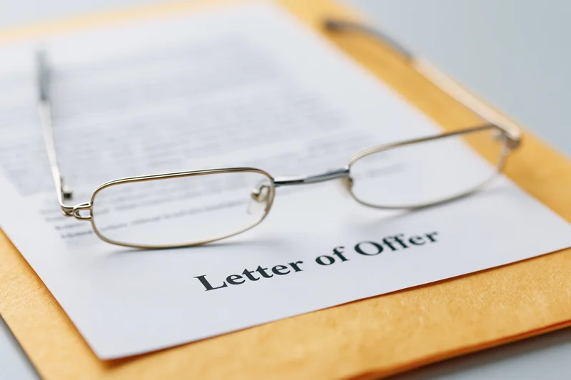 Reading glasses resting on a letter of offer placed on a clipboard