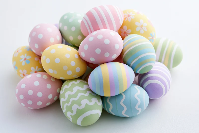 Pile of hand-painted easter eggs stacked loosely on white surface