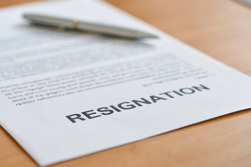 Printed resignation letter on wooden desk with pen resting on top
