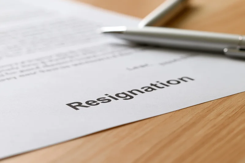 Resignation letter with bold heading on wooden desk, pen resting beside it