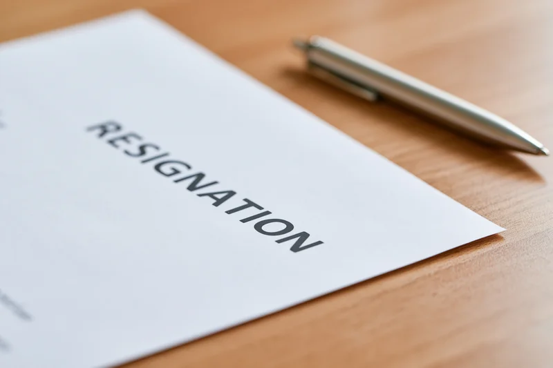 Resignation letter on wooden desk with pen
