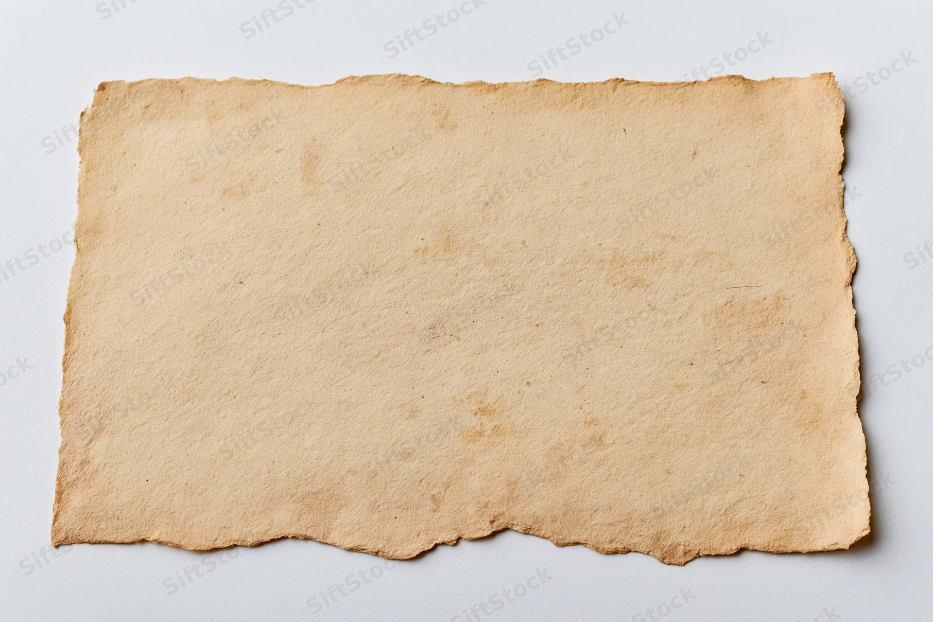 Aged blank paper card with deckled edges lying flat on white surface