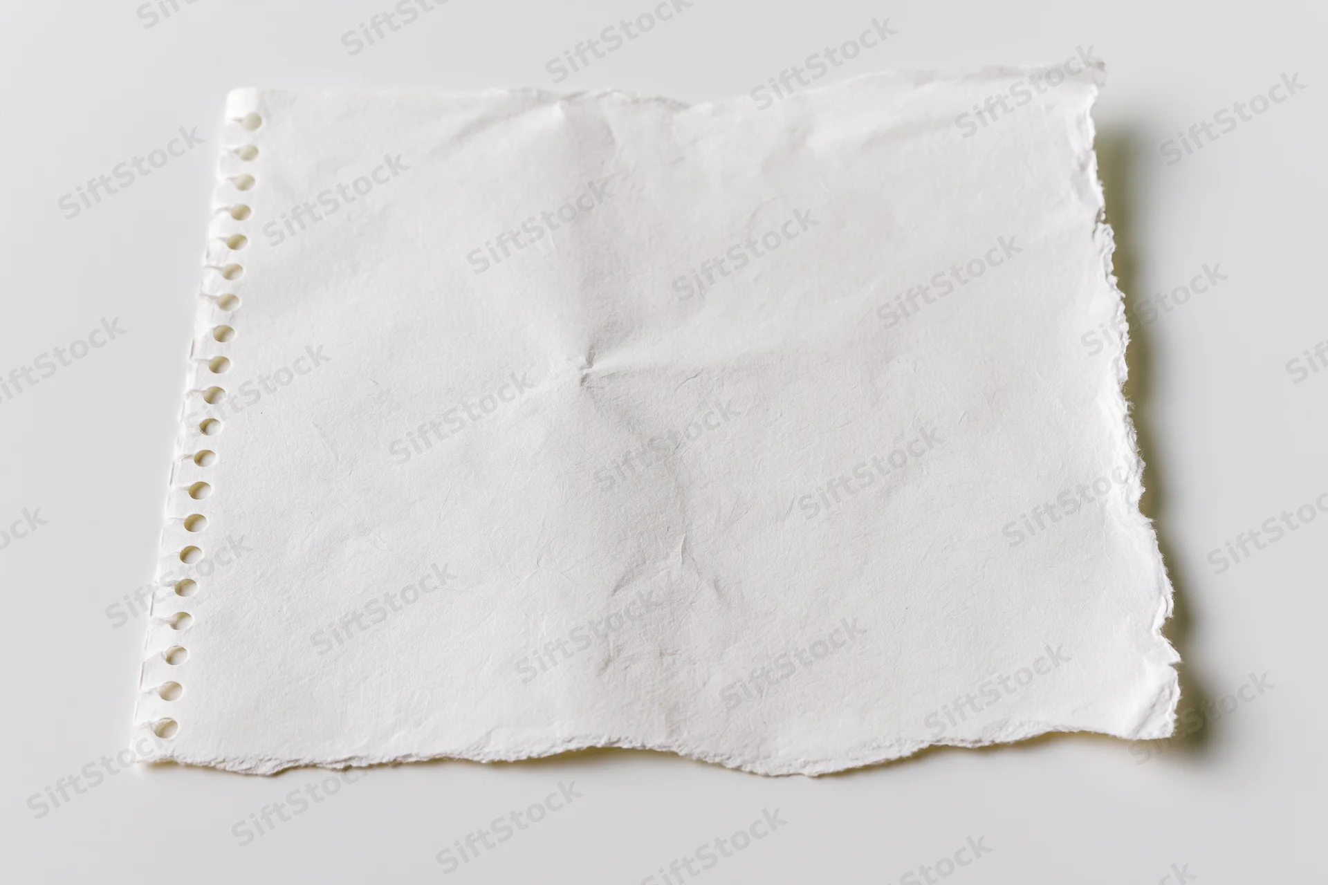 Torn blank notebook page with spiral binding lying flat on white surface