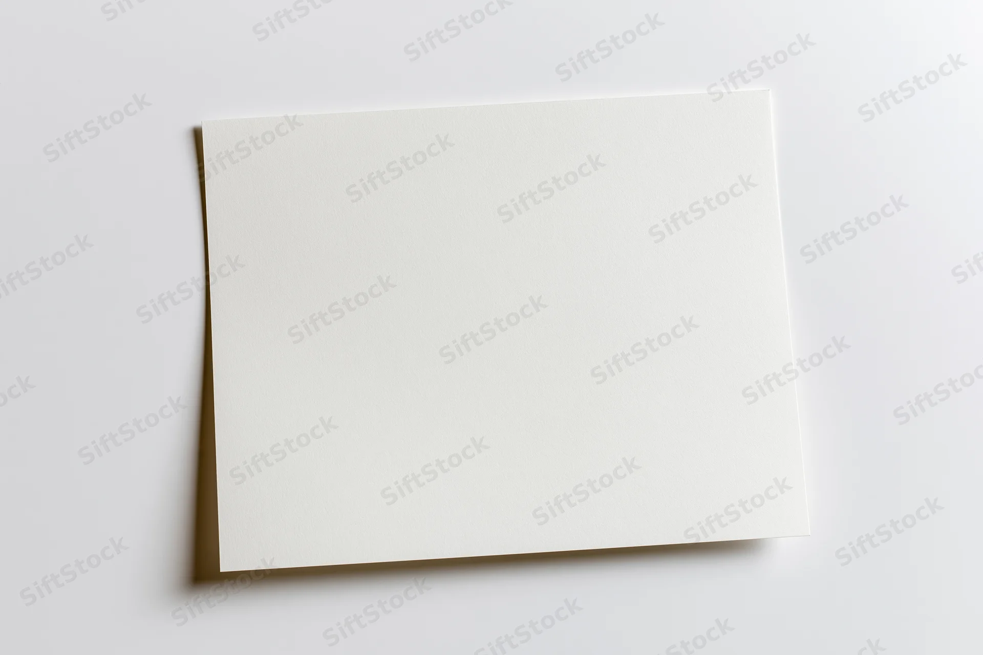 Blank white paper sheet lying flat on a light surface viewed from above