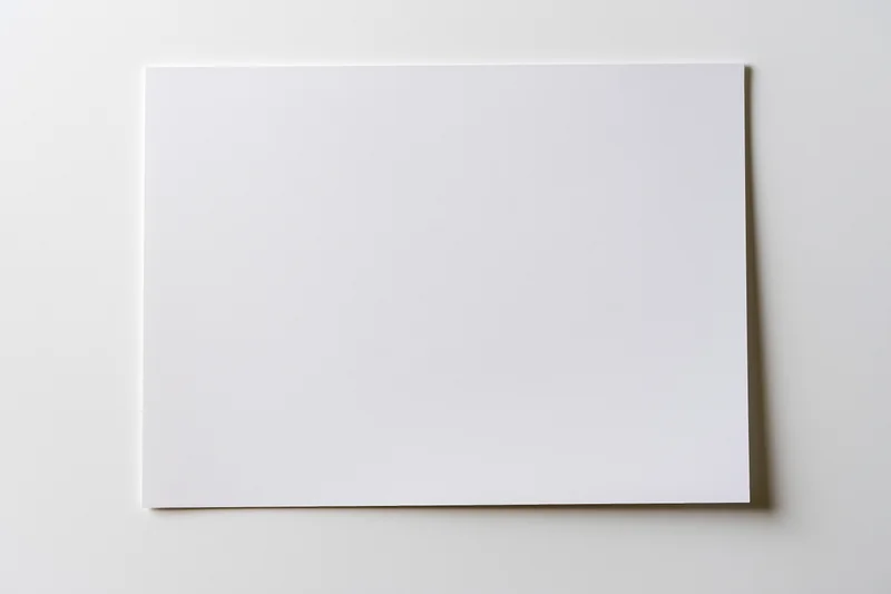 Blank white paper sheet lying flat on a light surface viewed from above