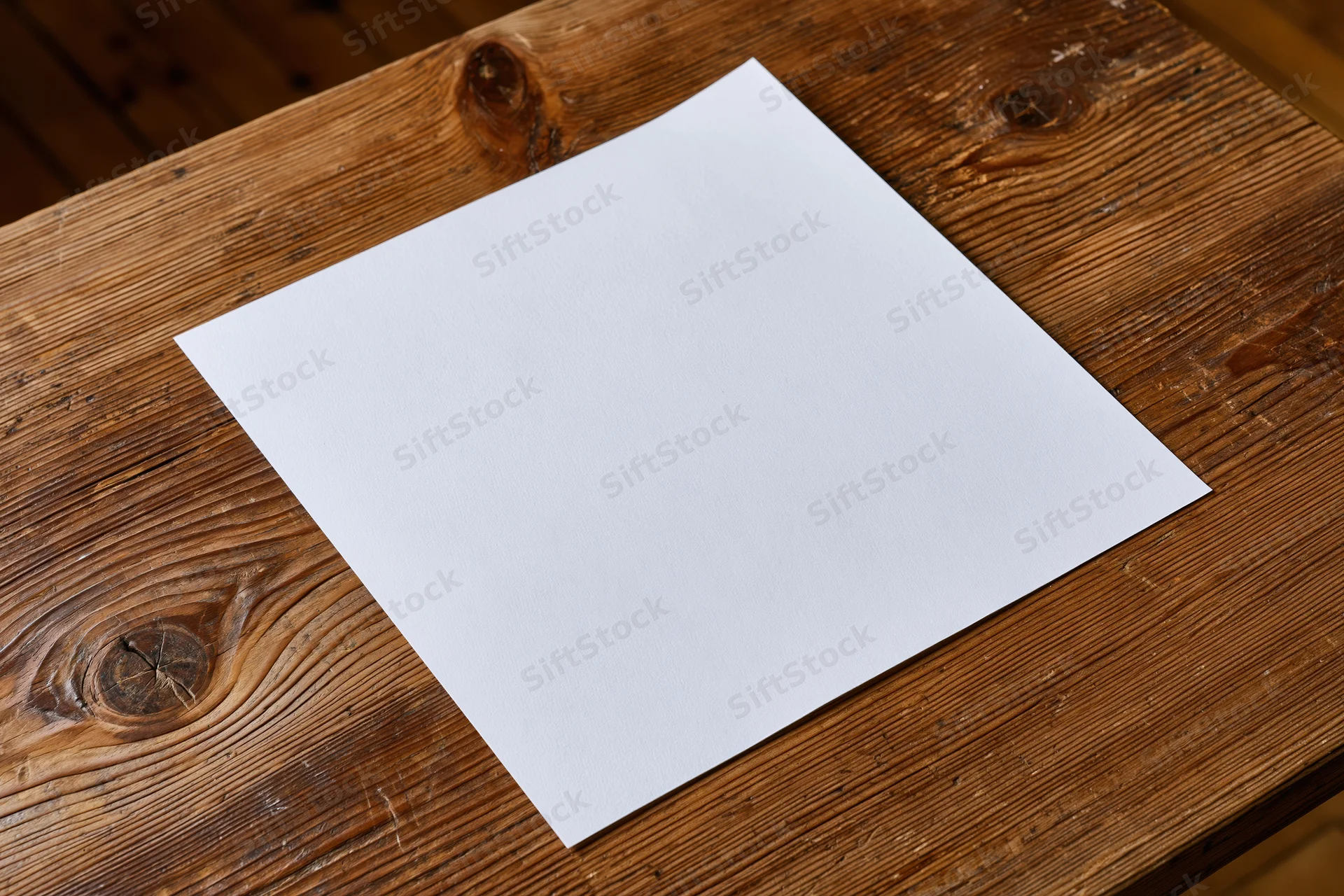 Blank white paper sheet lying flat on rustic wooden table surface