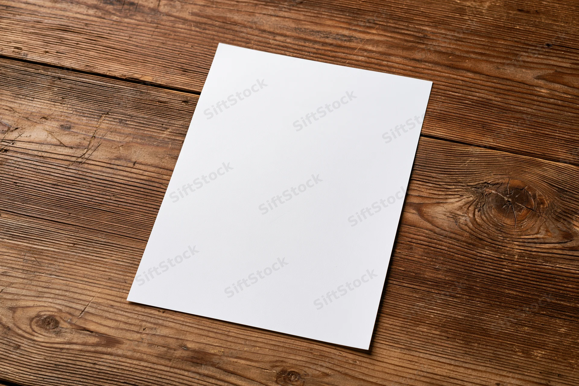 Blank white paper sheet lying flat on rustic wooden table surface