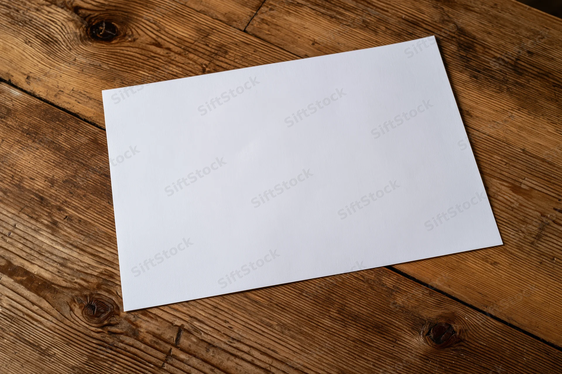 Blank white paper sheet lying flat on rustic wooden table surface