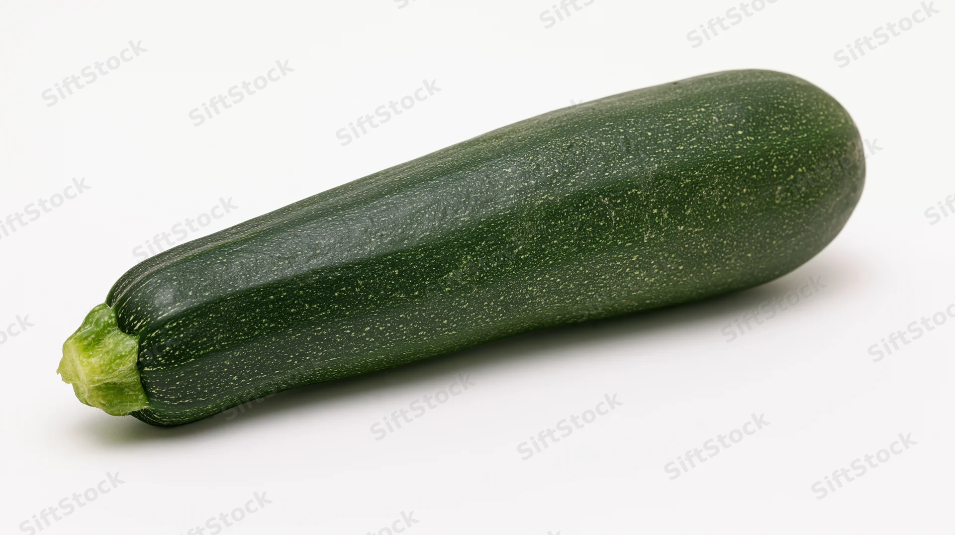 Single fresh zucchini lying horizontally on white background
