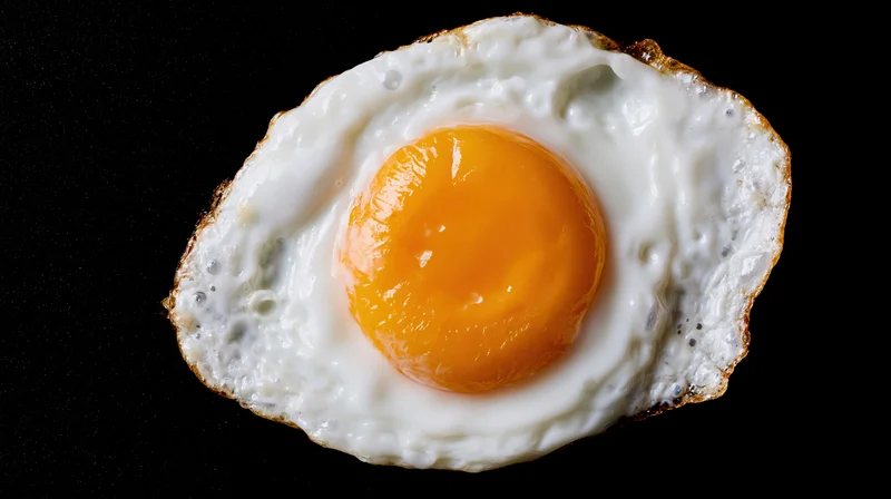 Fried egg sunny-side-up on black background