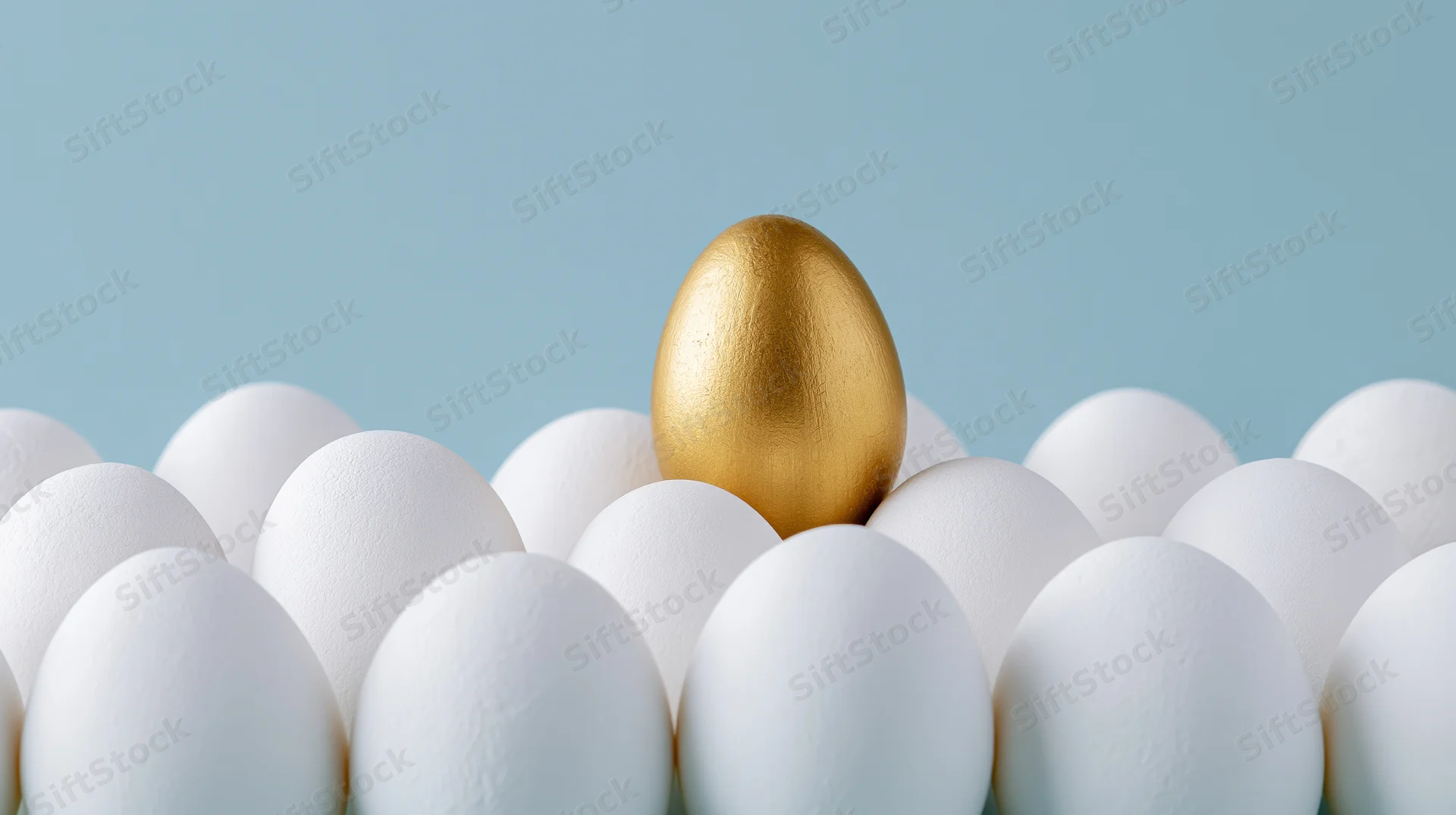 Golden egg standing among white eggs on a blue background