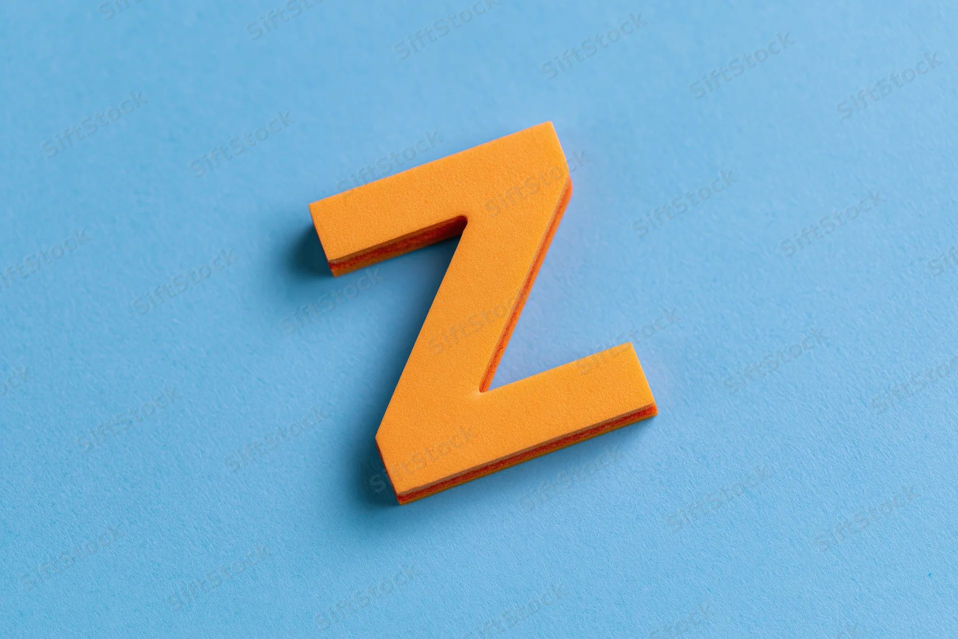 Orange foam letter z on a bright blue surface