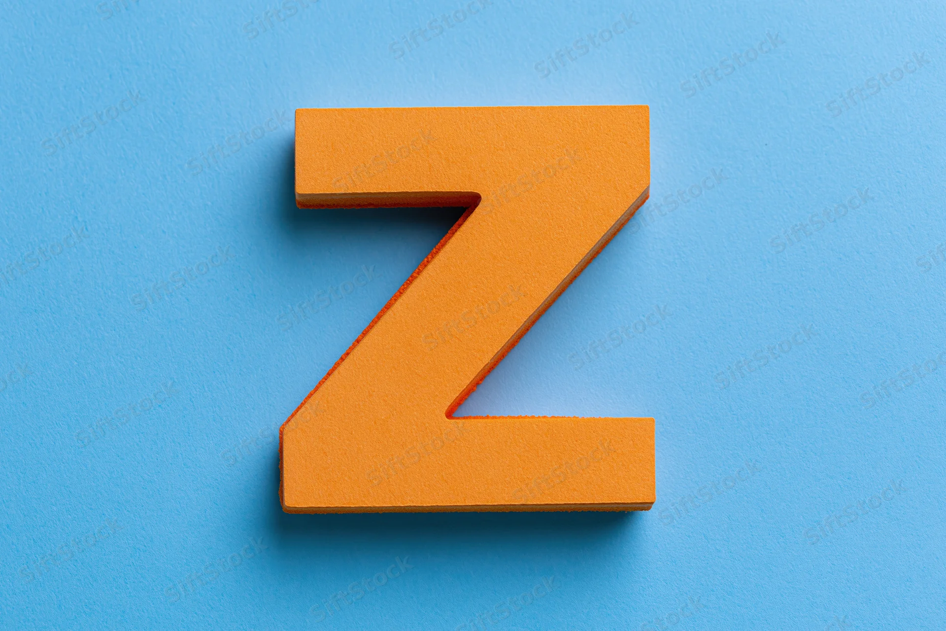 Orange foam letter z centered on a flat bright blue surface