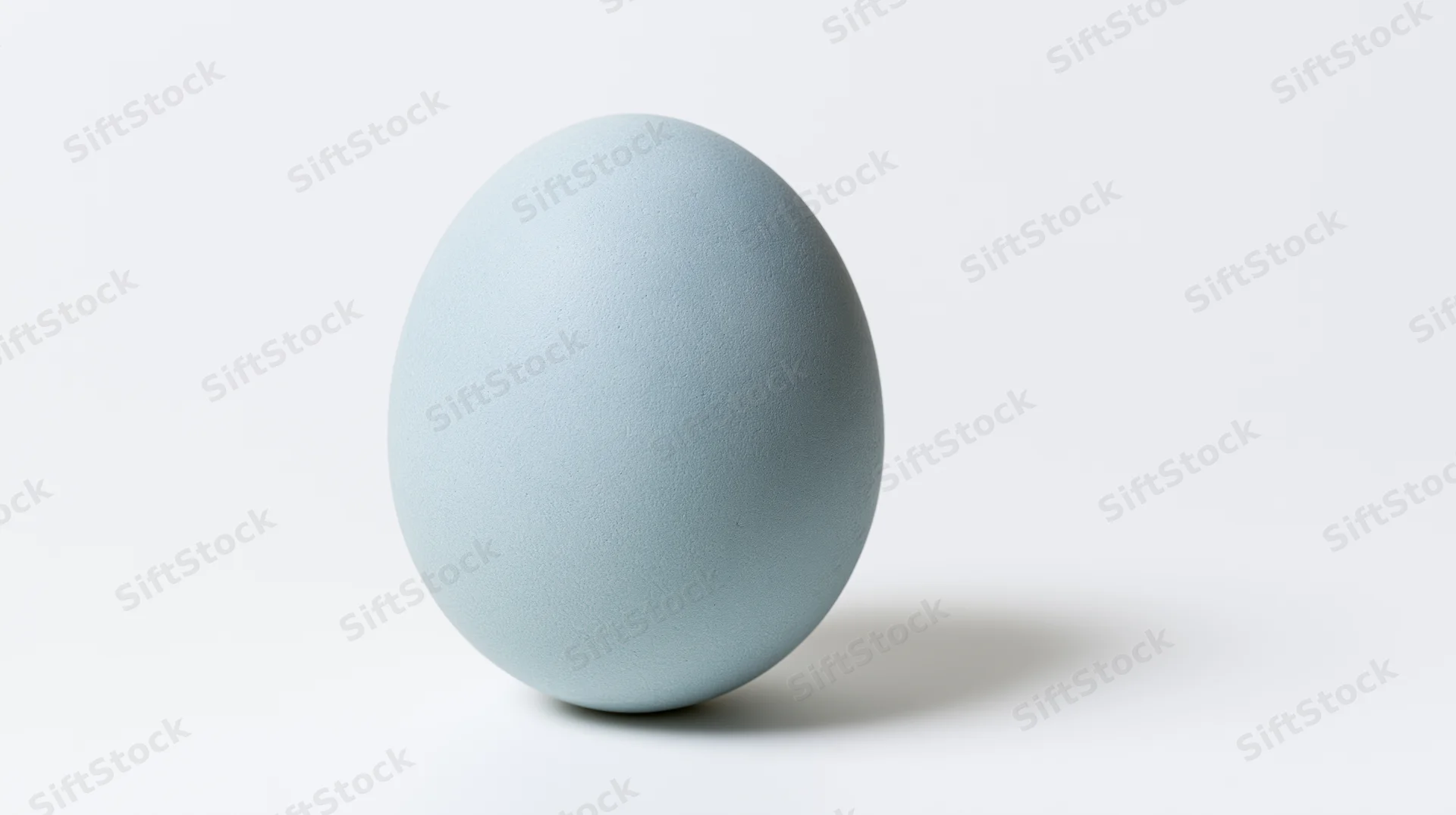Pale blue egg standing upright on white background