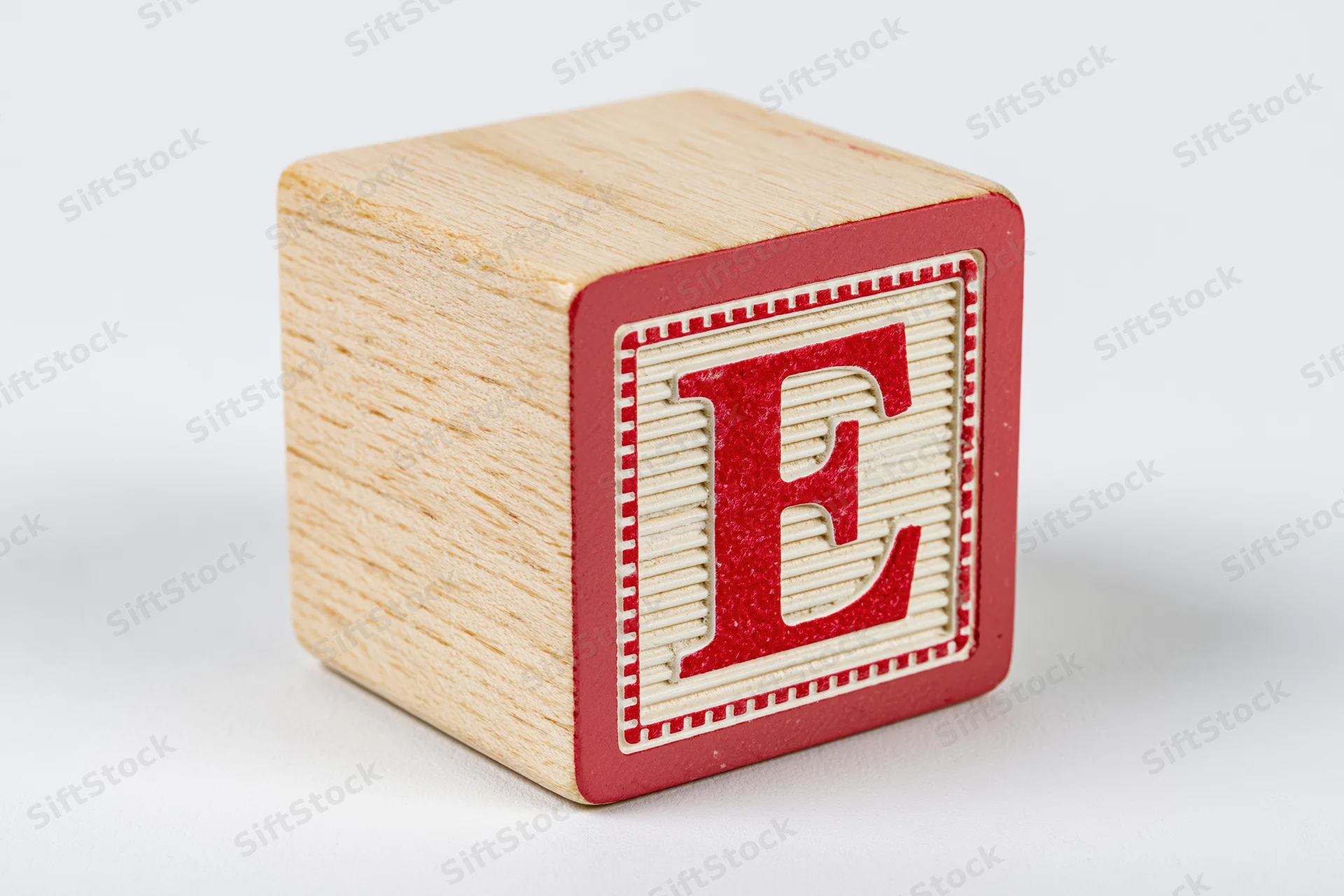 Wooden alphabet block with red letter e on white background