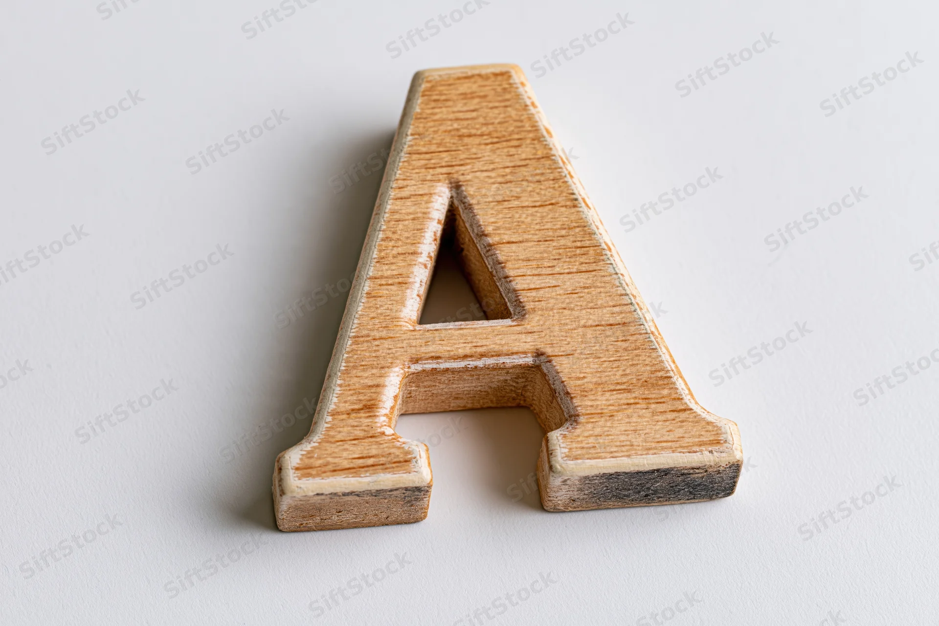 Wooden letter a toy block lying flat on white surface