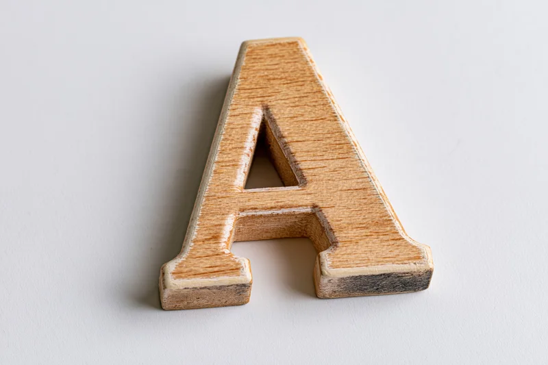 Wooden letter a toy block lying flat on white surface