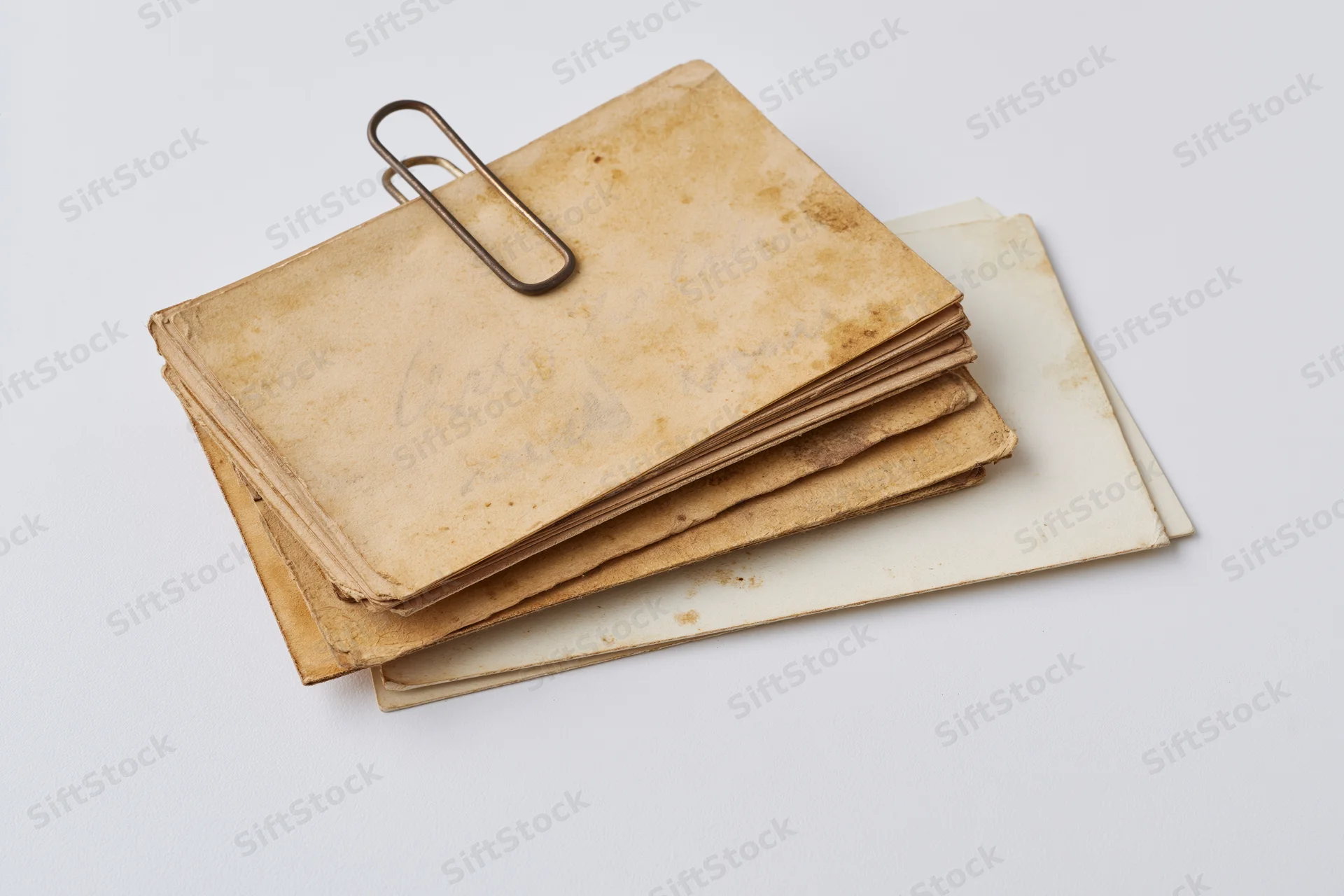 Stack of aged yellowed paper cards and postcards on white background