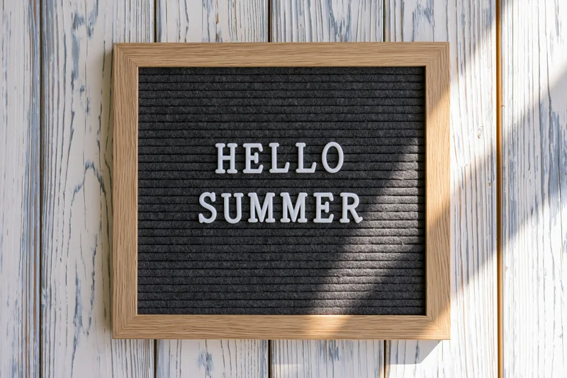 Letterboard with hello summer text mounted on a wooden wall