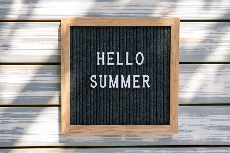Letterboard with hello summer text mounted on weathered wooden wall