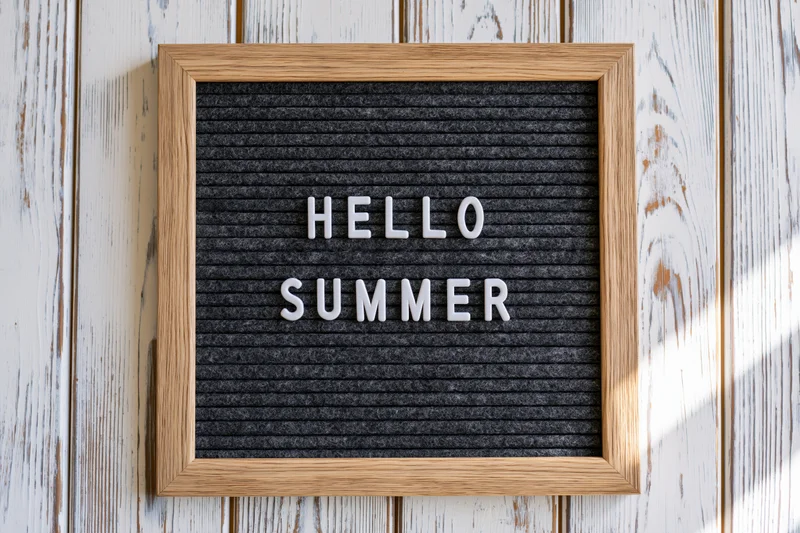 Letterboard with hello summer text mounted on whitewashed wood wall