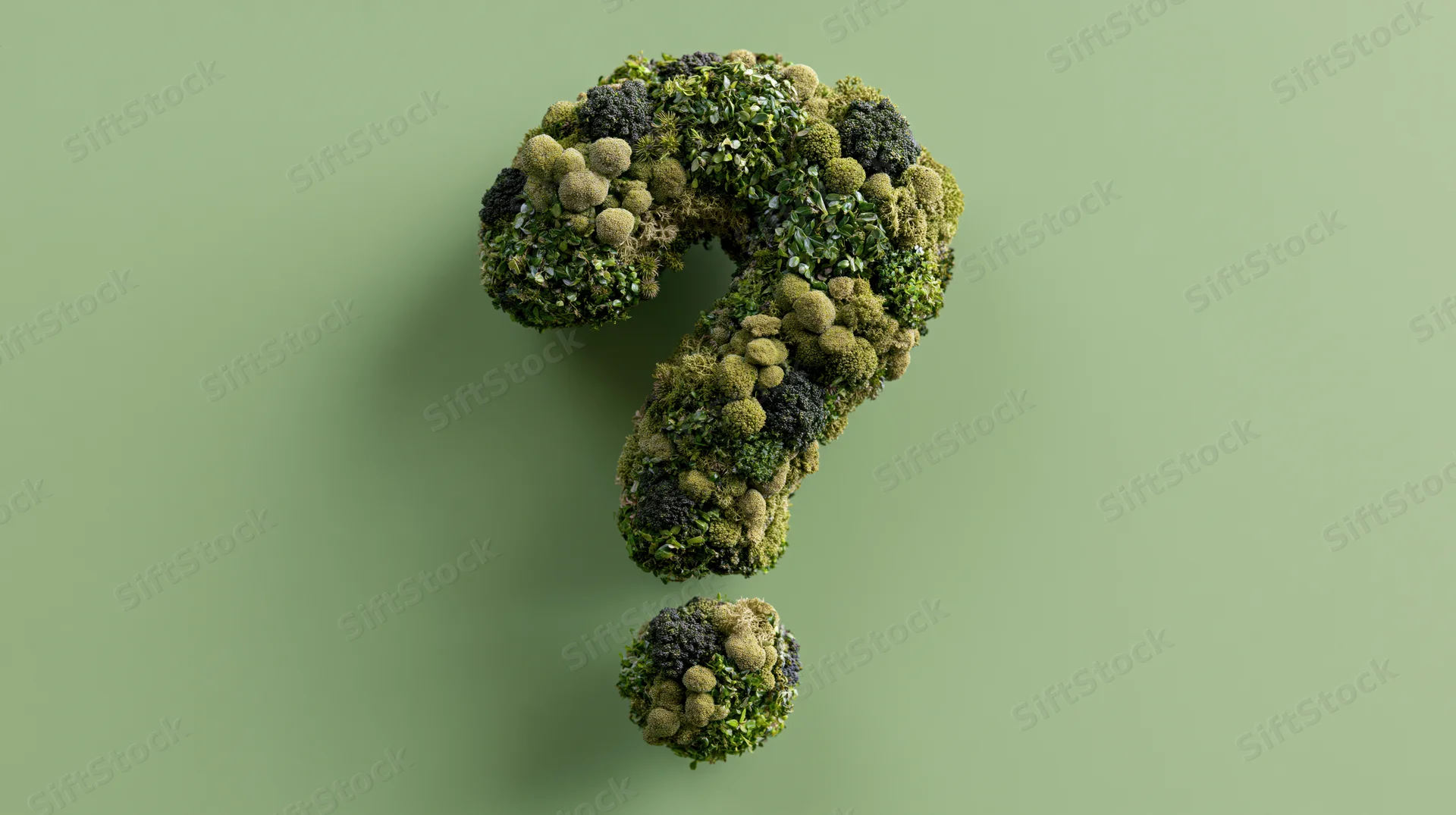 Three-dimensional question mark sculpture covered in moss and green foliage against a plain green background