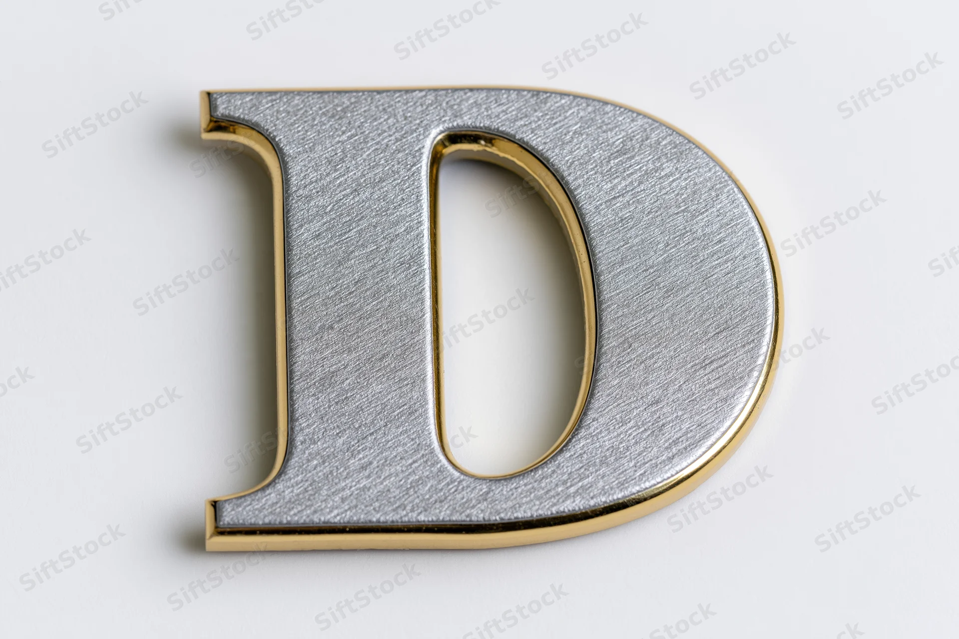 Three-dimensional uppercase letter d with matte silver face and gold trim on white background
