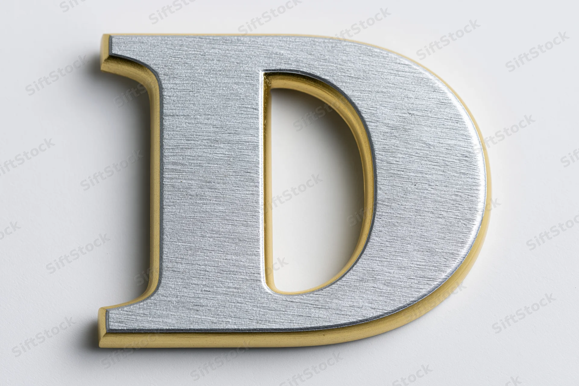 Three-dimensional uppercase letter d with brushed silver face and gold trim on white background