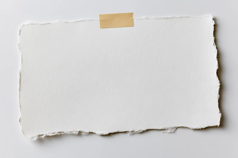 Torn white paper held by beige tape on plain surface