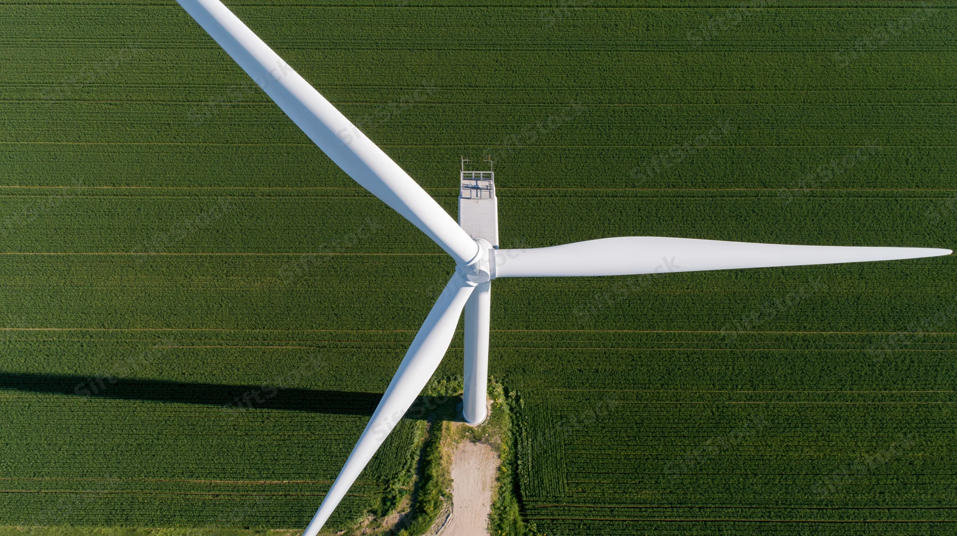 Aerial top-down view of a wind turbine in a green agricultural field