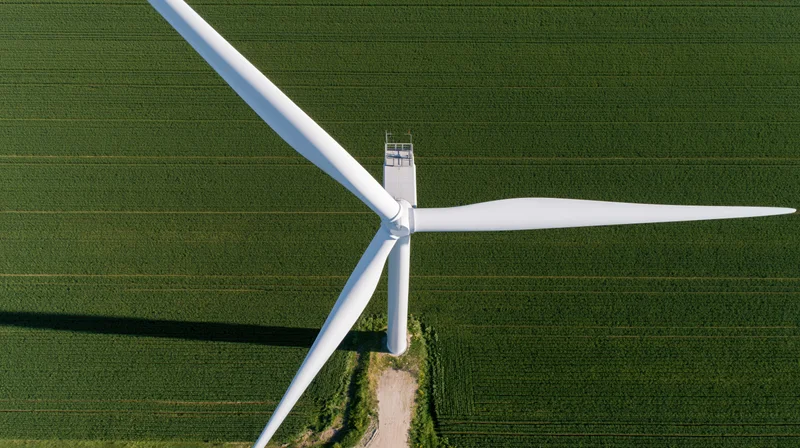 Aerial top-down view of a wind turbine in a green agricultural field