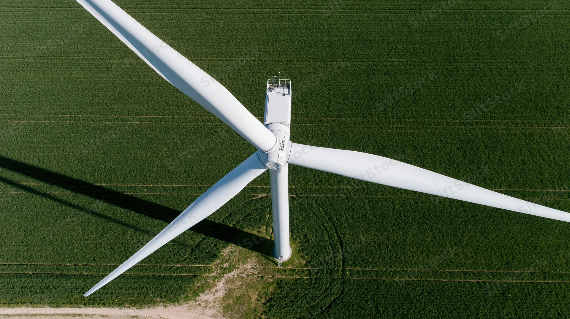 Aerial view of a wind turbine standing in a green agricultural field