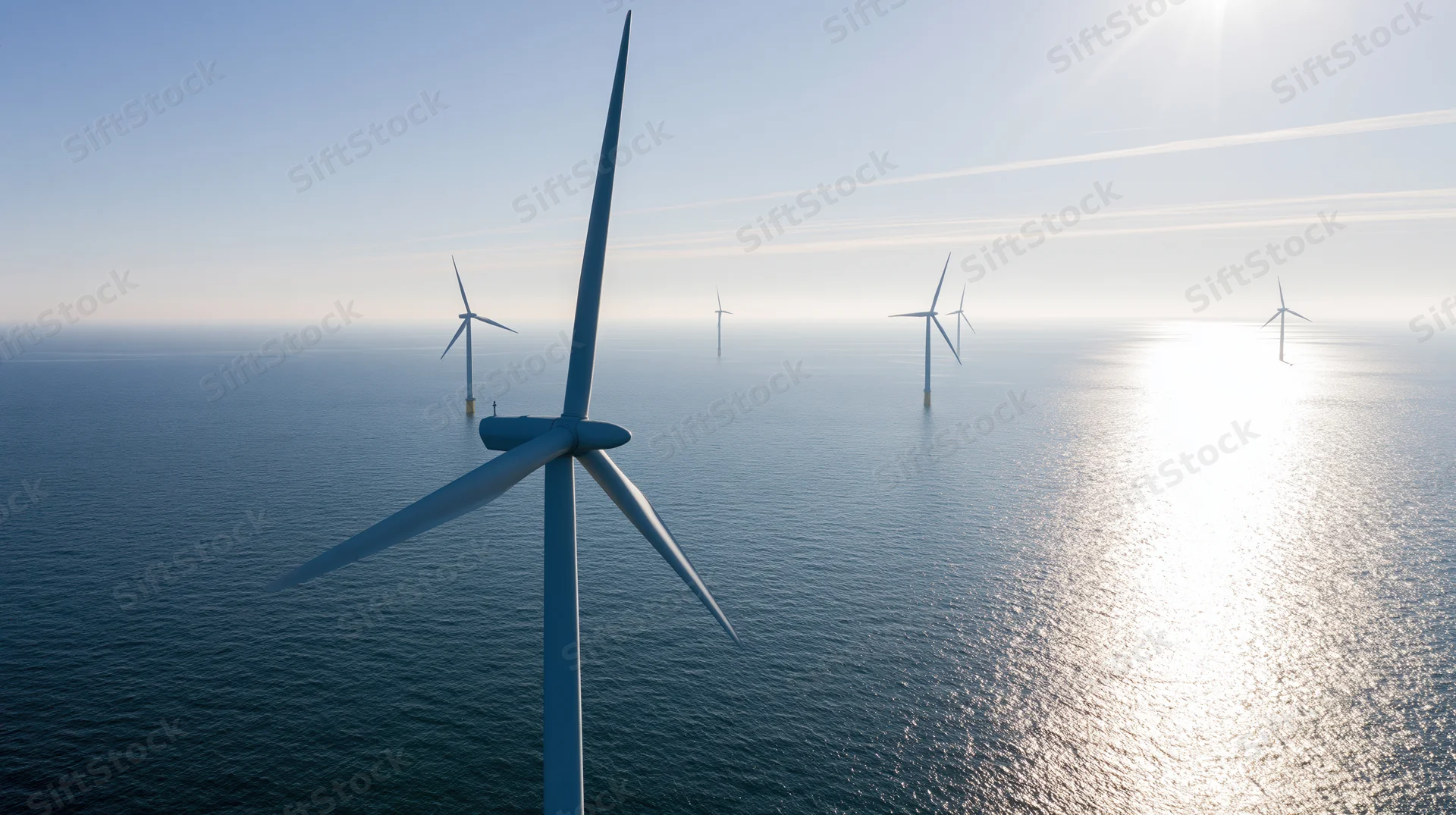 Offshore wind turbines rising from open ocean under bright sun