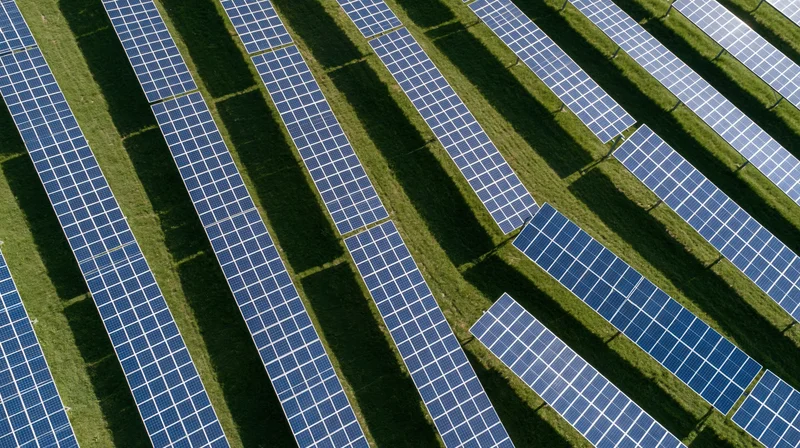 Aerial view of rows of photovoltaic panels in a grassy field