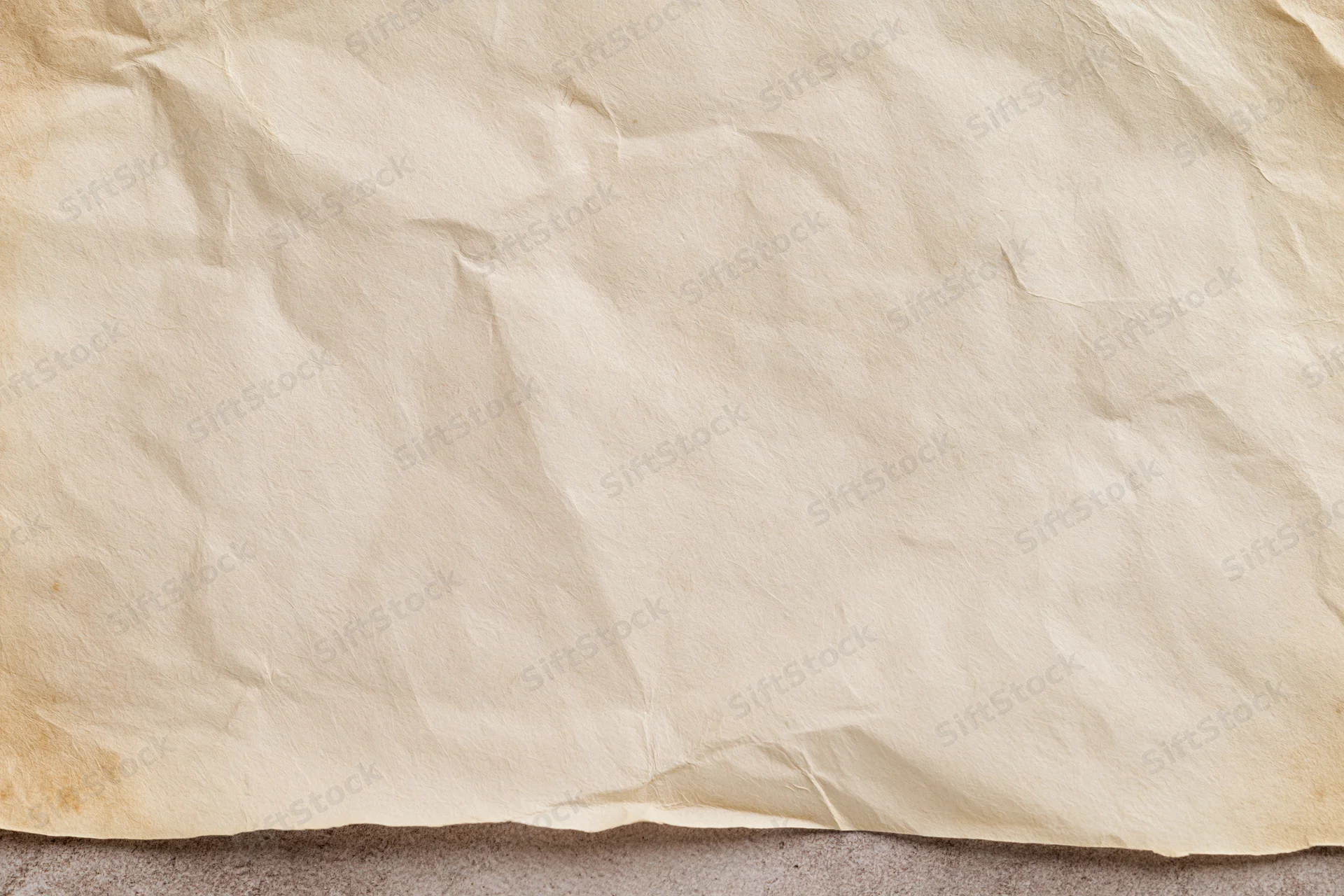 Closeup of aged crumpled paper sheet lying flat on textured surface