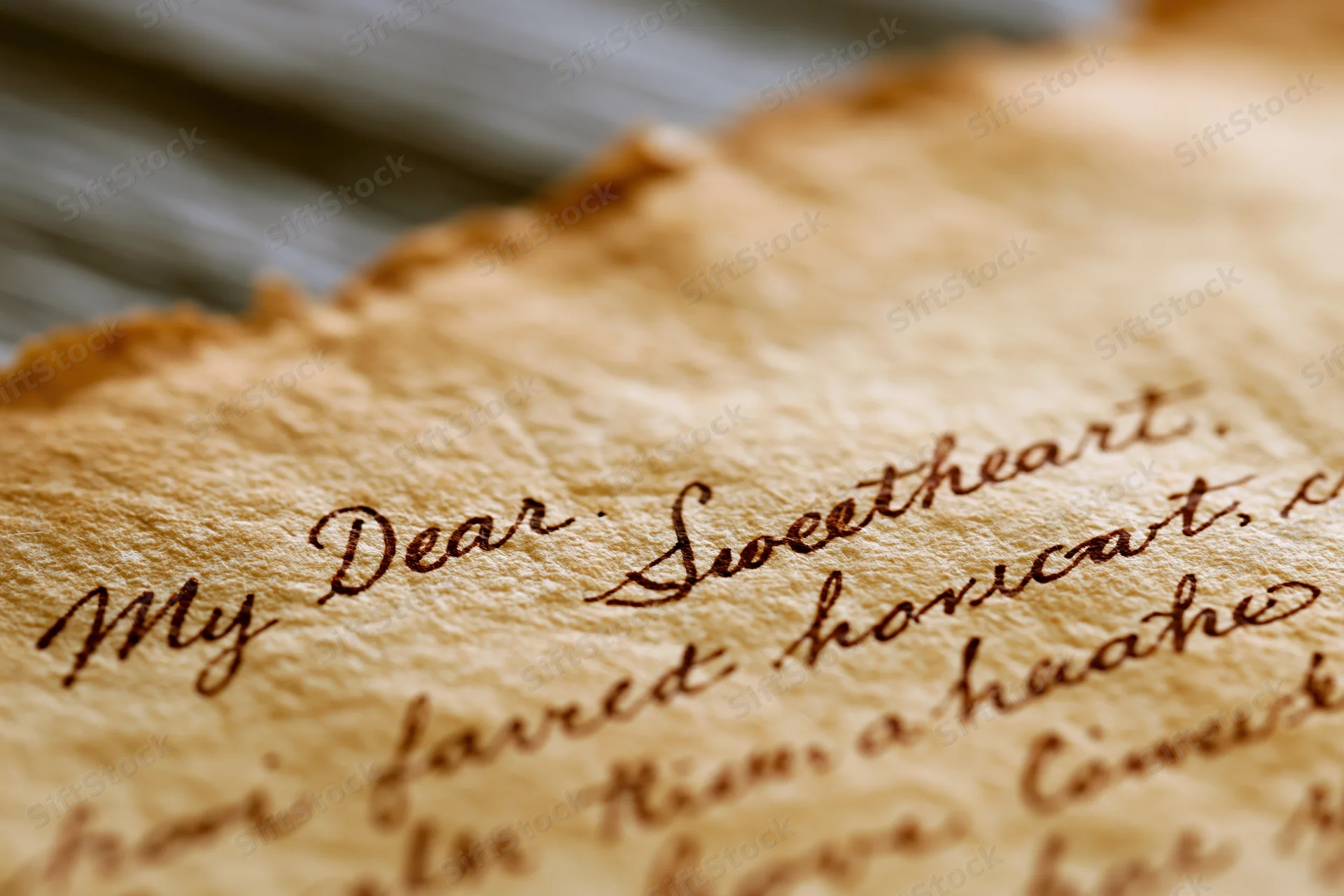 Close-up of aged handwritten love letter on yellowed parchment paper with cursive script reading "My Dear Sweetheart