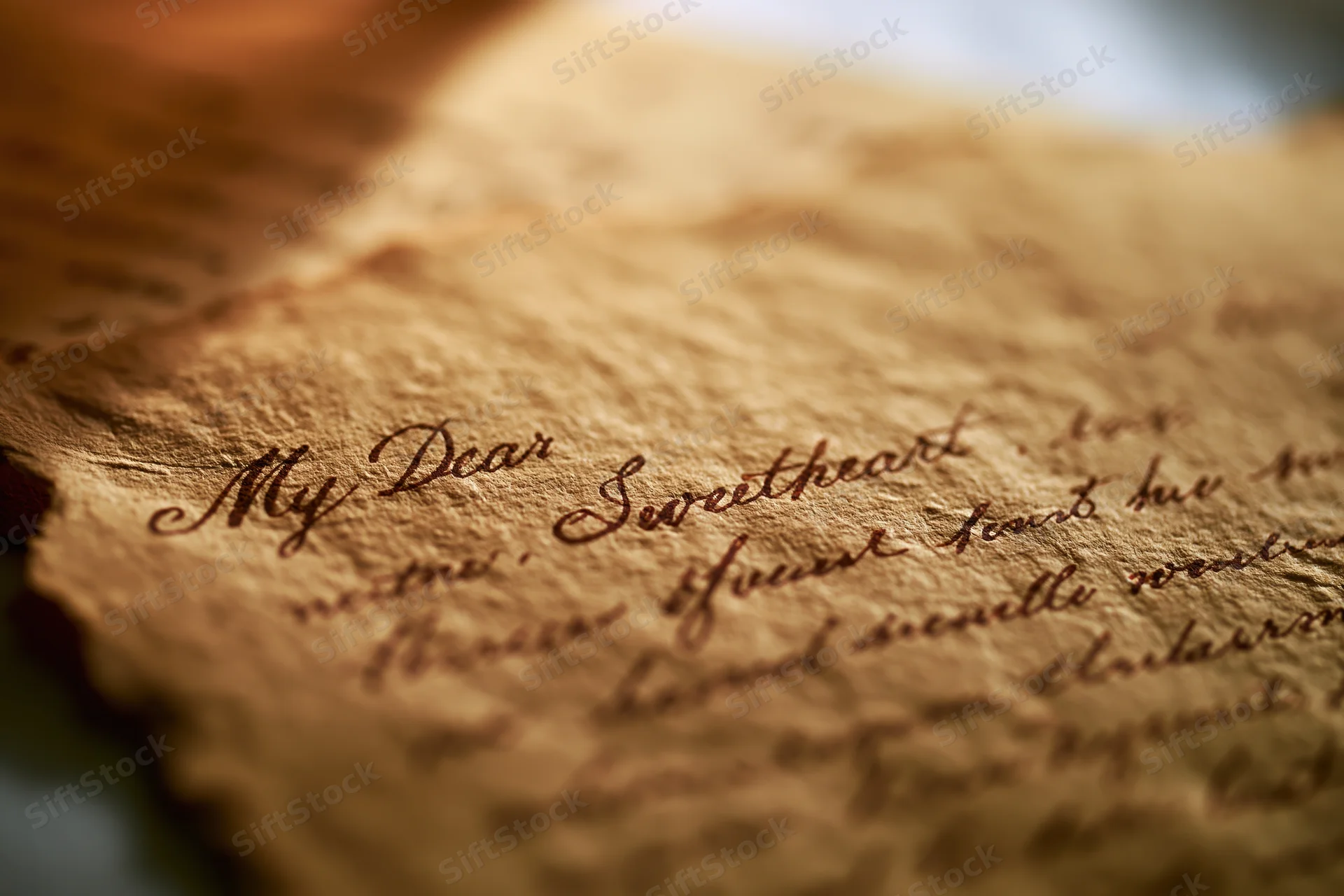 Close-up of an aged handwritten love letter on yellowed parchment paper with cursive script reading "My Dear Sweetheart
