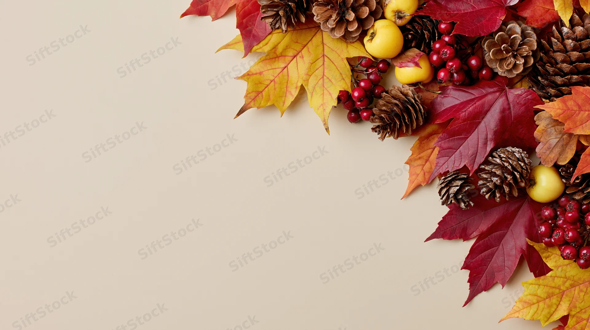 Autumn leaves and pinecones arranged in corner on beige background with copyspace